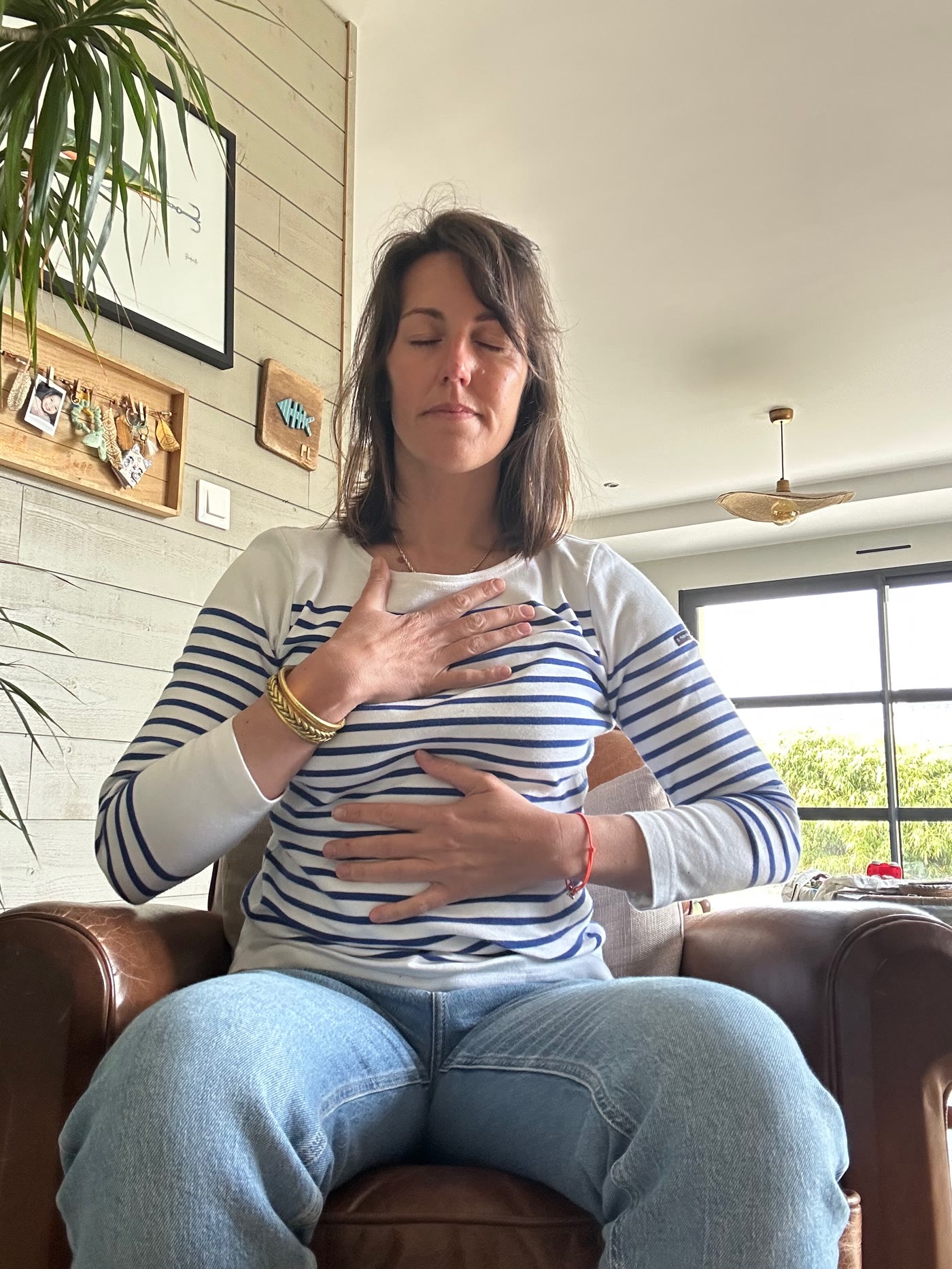 Femme assise, mains posées sur la poitrine, yeux fermés